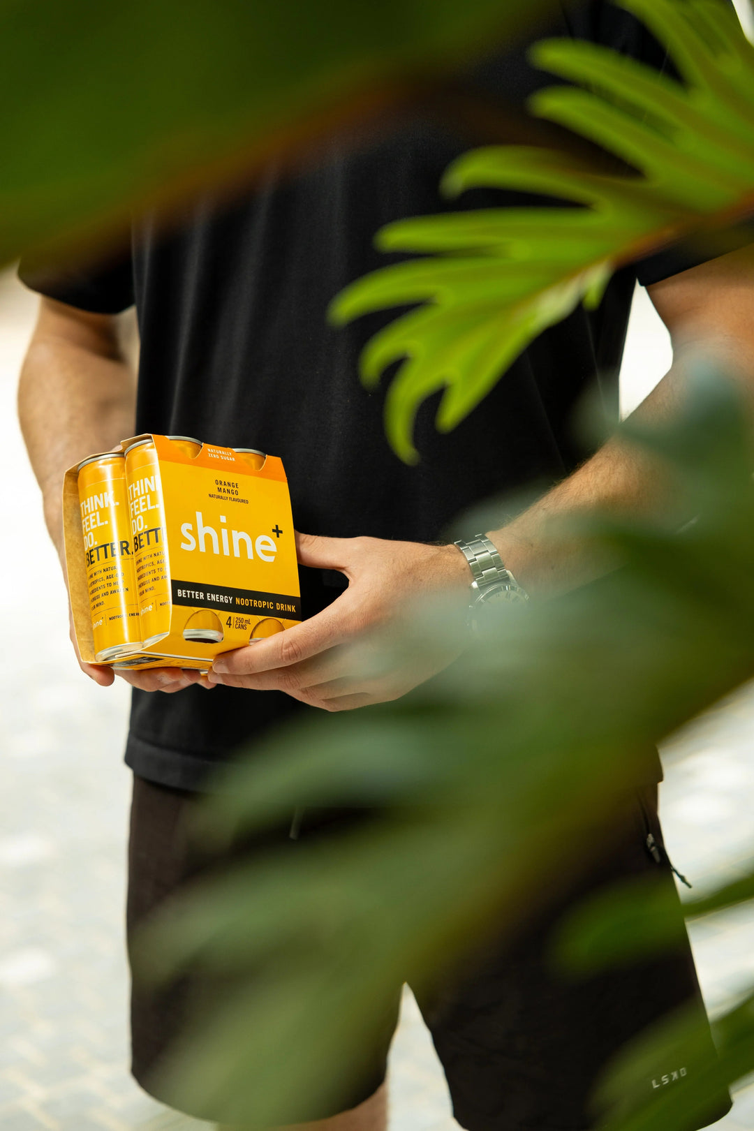 Person holding orange mango nootropic drink pack outdoors, focus and energy beverage