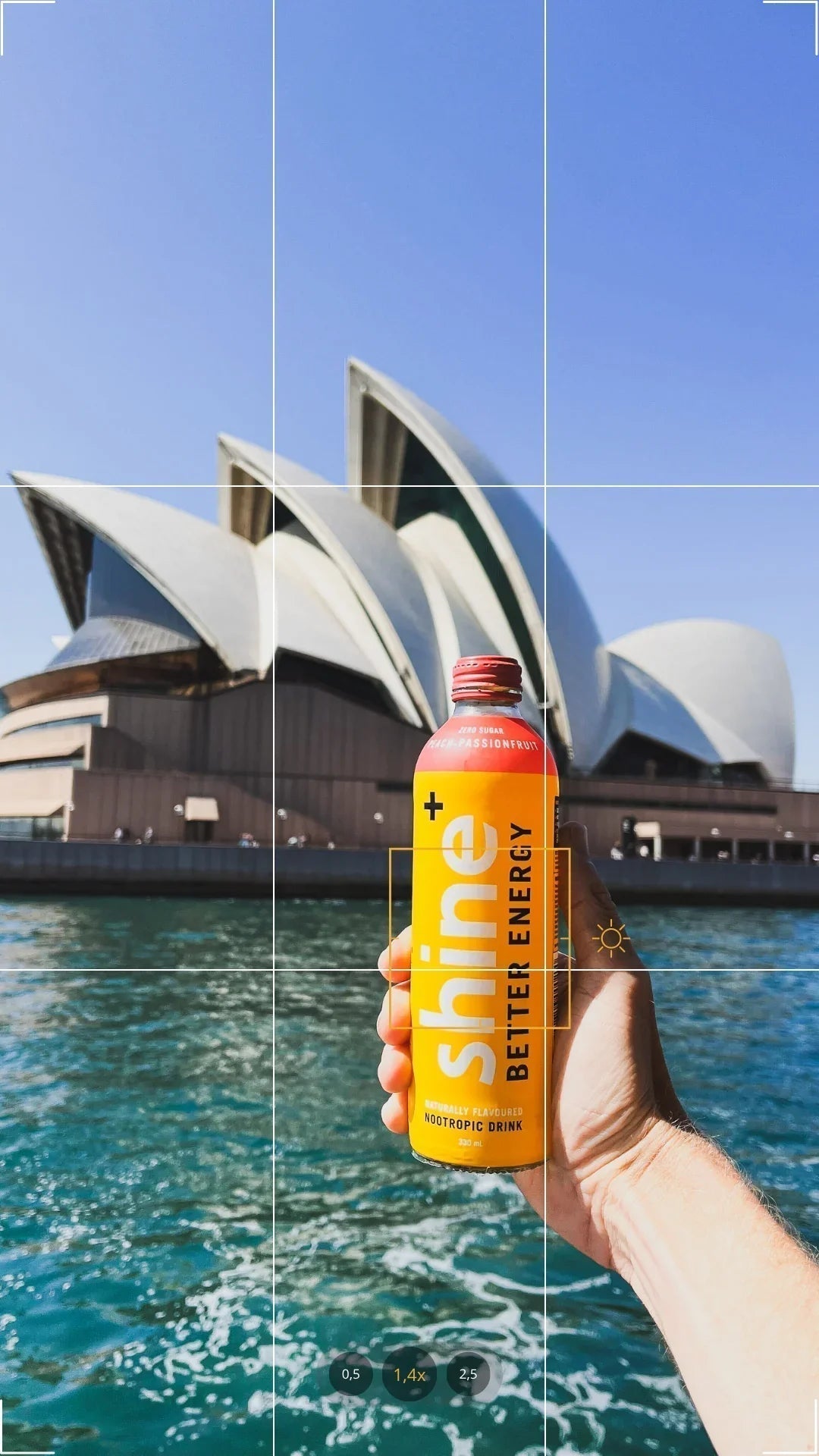 Hand holding a nootropic drink can with Sydney Opera House and blue sky in background