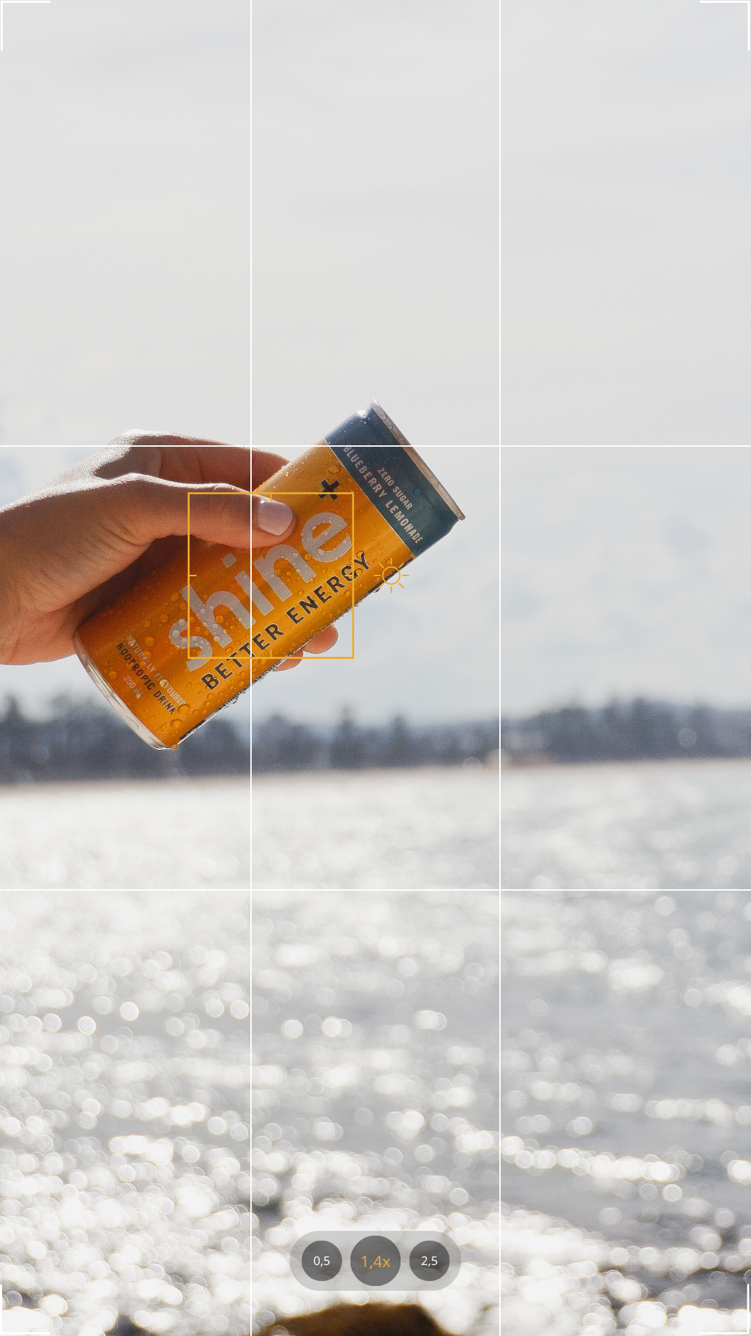 Hand holding a yellow nootropic energy drink can outdoors by sparkling water