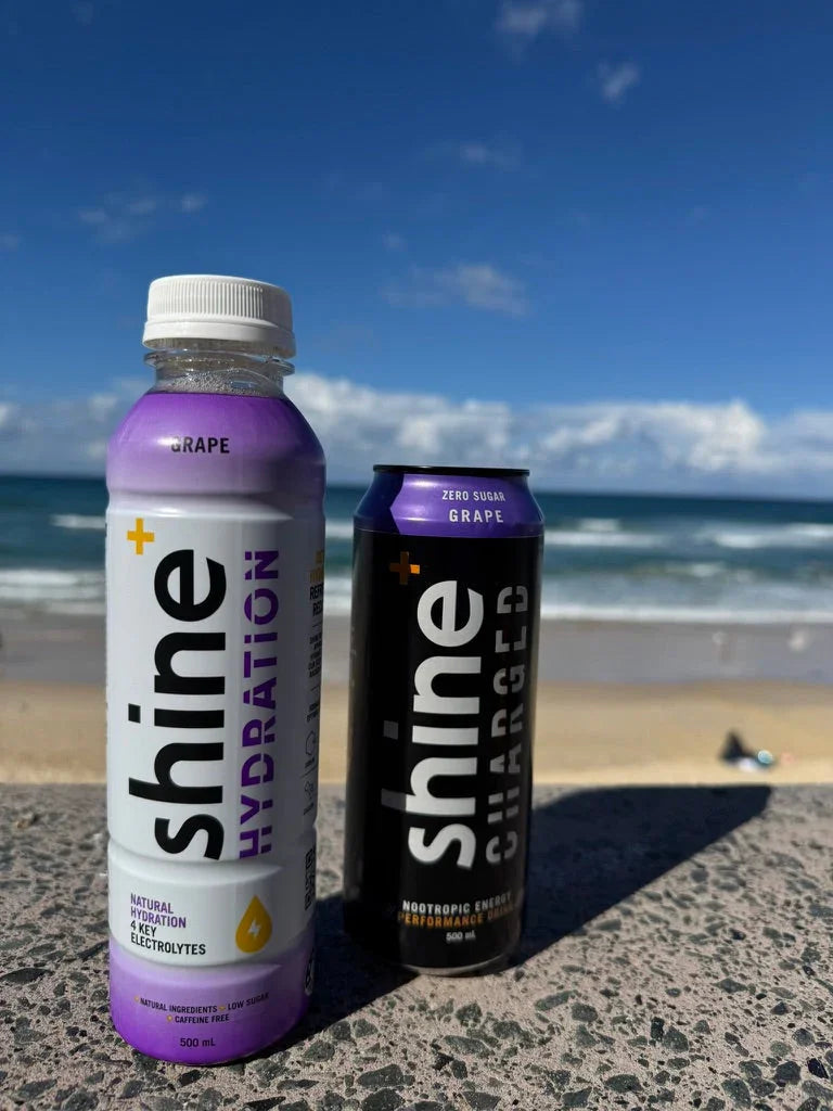 Grape-flavored hydration and nootropic energy drinks on a beach with blue sky background
