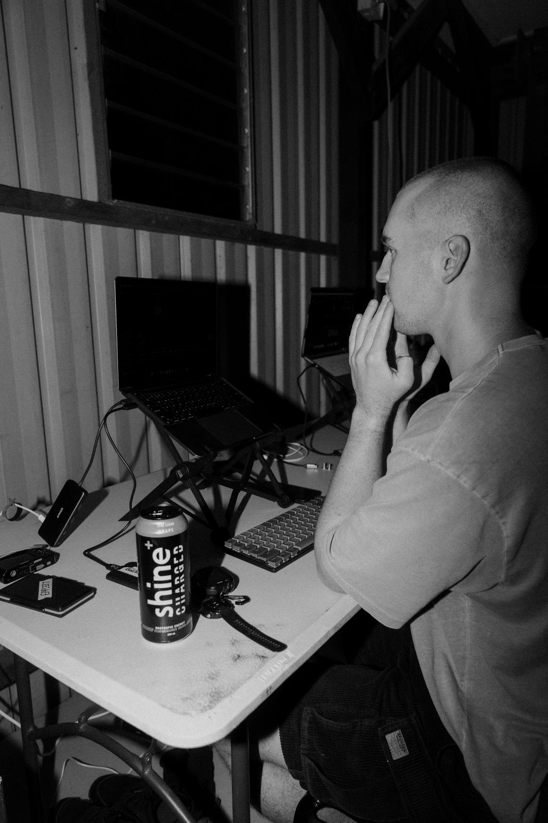 Man working at desk with laptop and can of nootropic drink, focused workspace setting