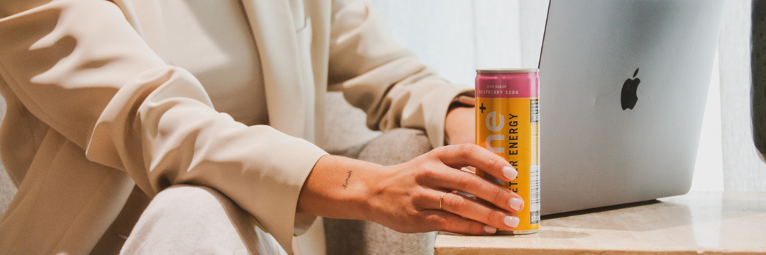 Person holding a nootropic energy drink can near a laptop, promoting brain-boosting focus