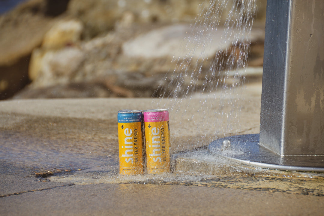 Two cans of natural nootropic energy drink by a water fountain outdoors on concrete