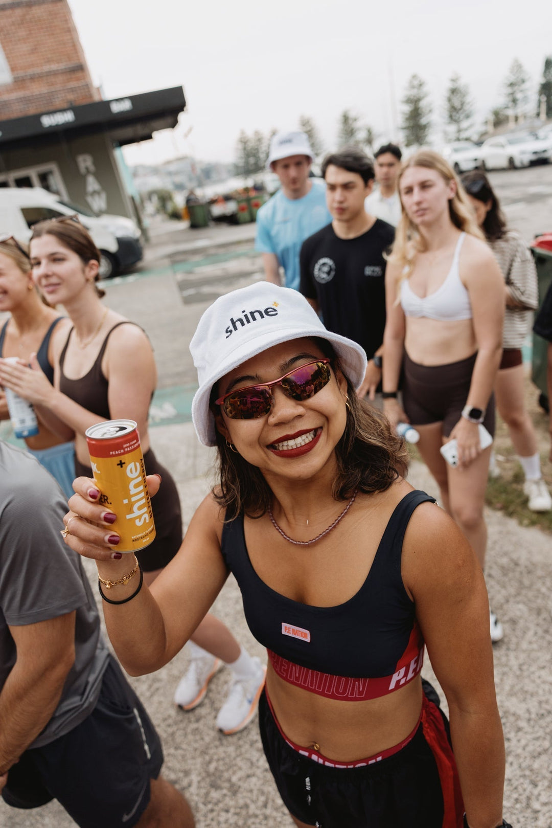 Woman in sportswear holding can of nootropic drink outdoors with active group