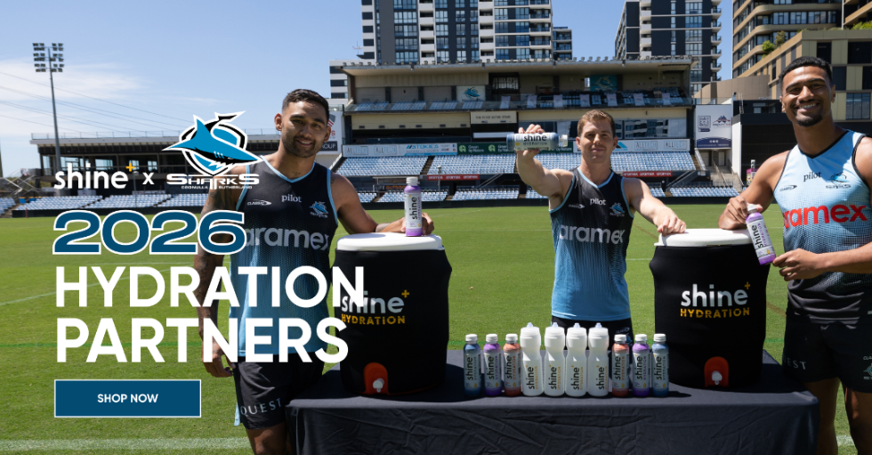 Three rugby players on a stadium field holding Shine hydration drinks with branded coolers and bottles.